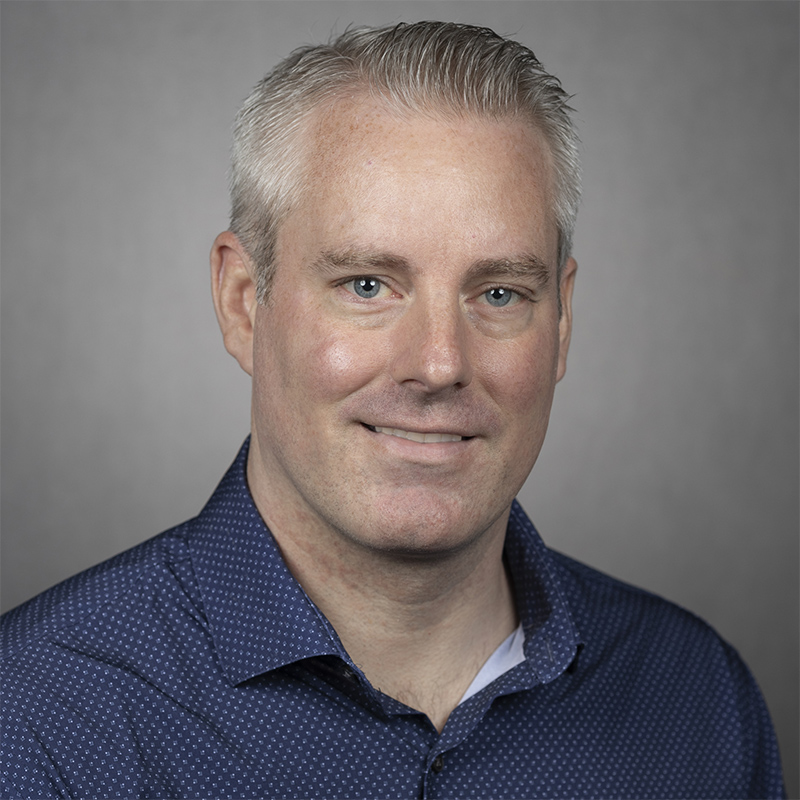 Marc Chevrette, a white male wearing dark blue collared shirt poses for a portrait