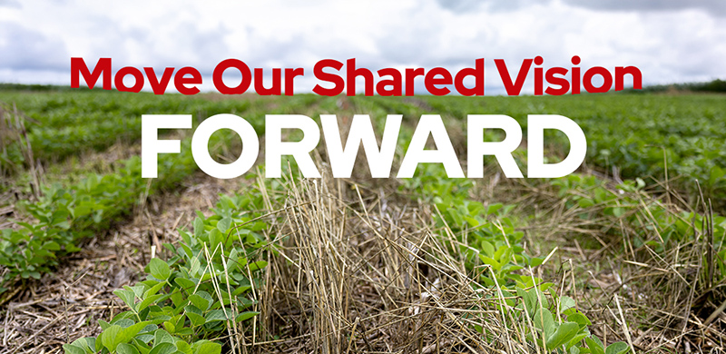 Image of gricultural field in the foreground, with a cloudy blue sky. Text "Move Our Shared Vision Forward" is overlayed.