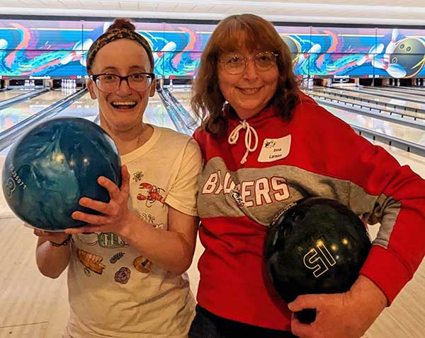 two woman hold bowling balls