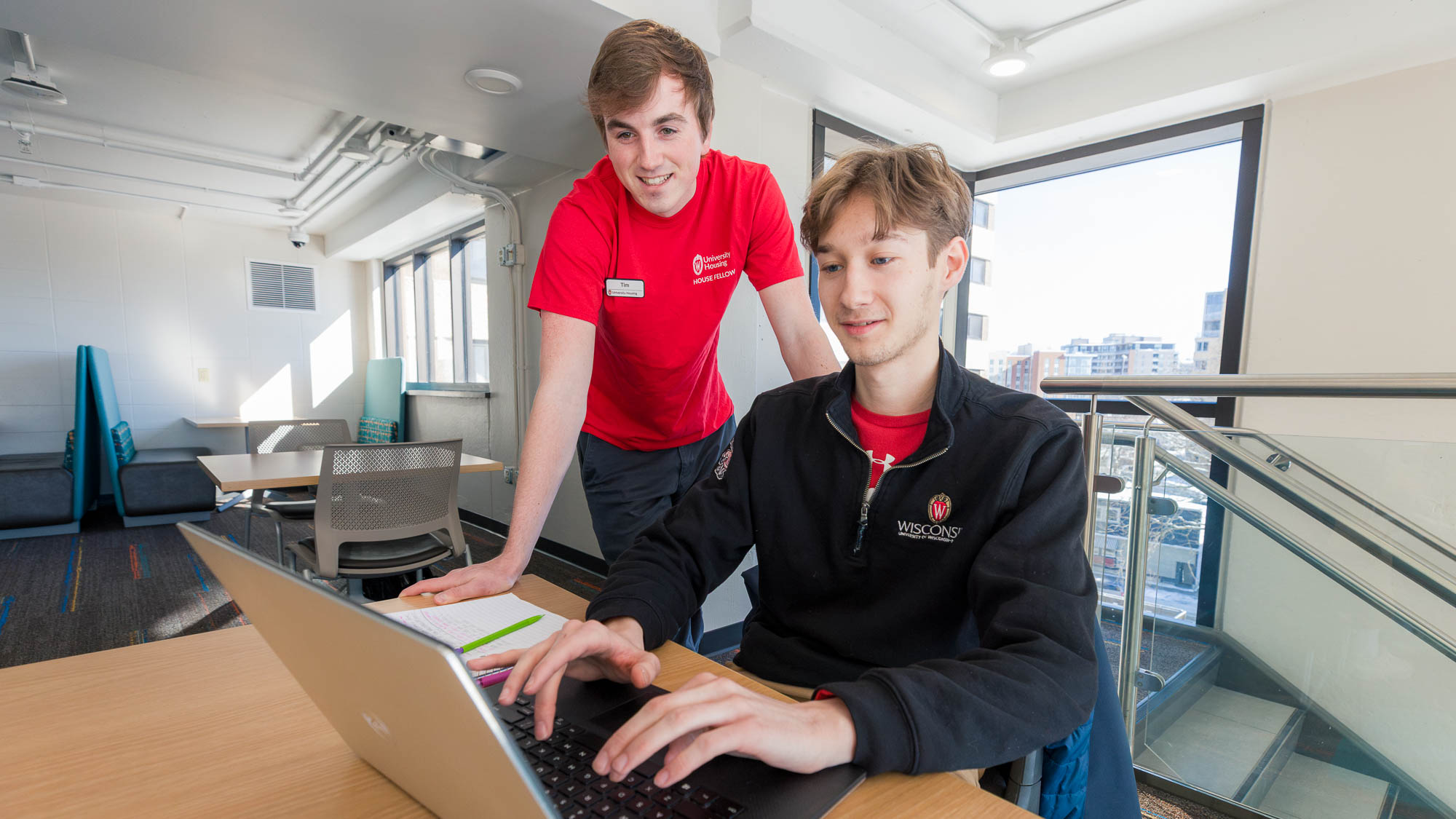 A resident and a House Fellow looking at a laptop computer together in a lounge