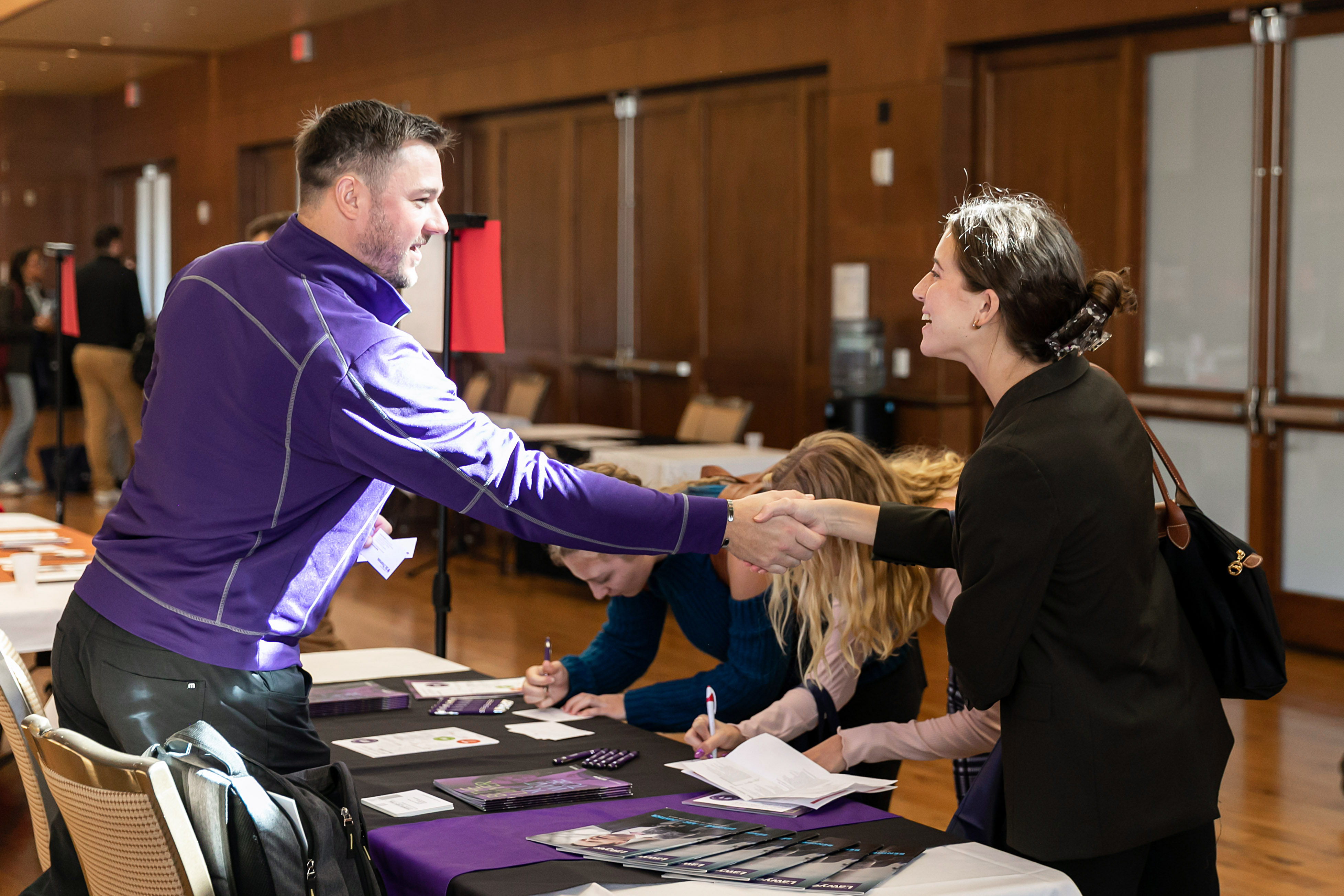 A man and a woman shaking hands at the Law School Expo