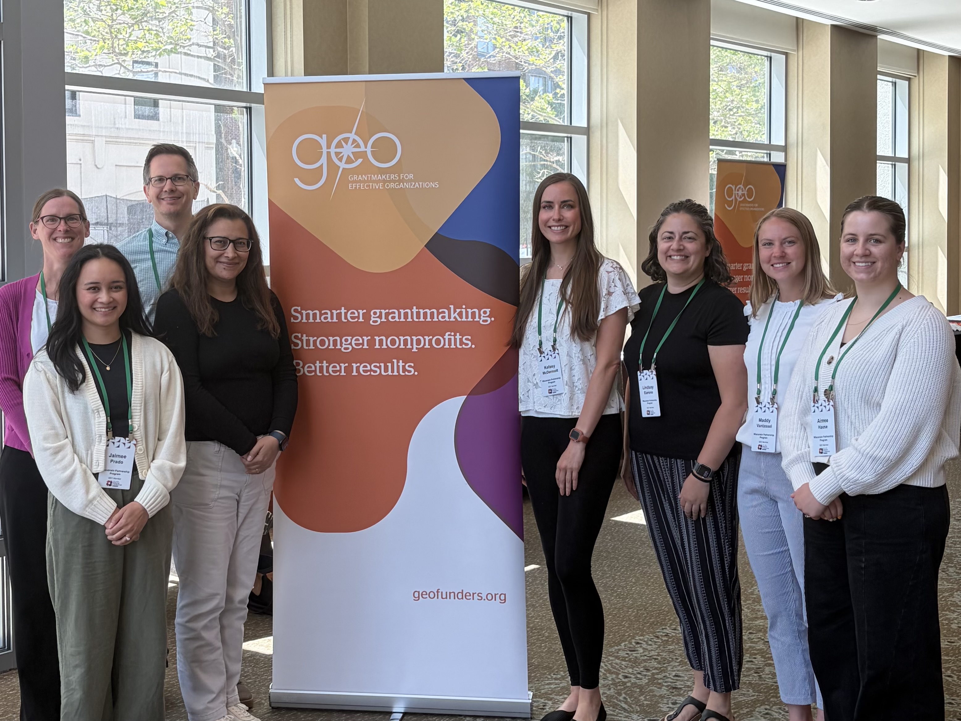 staff members stand next to conference banner 