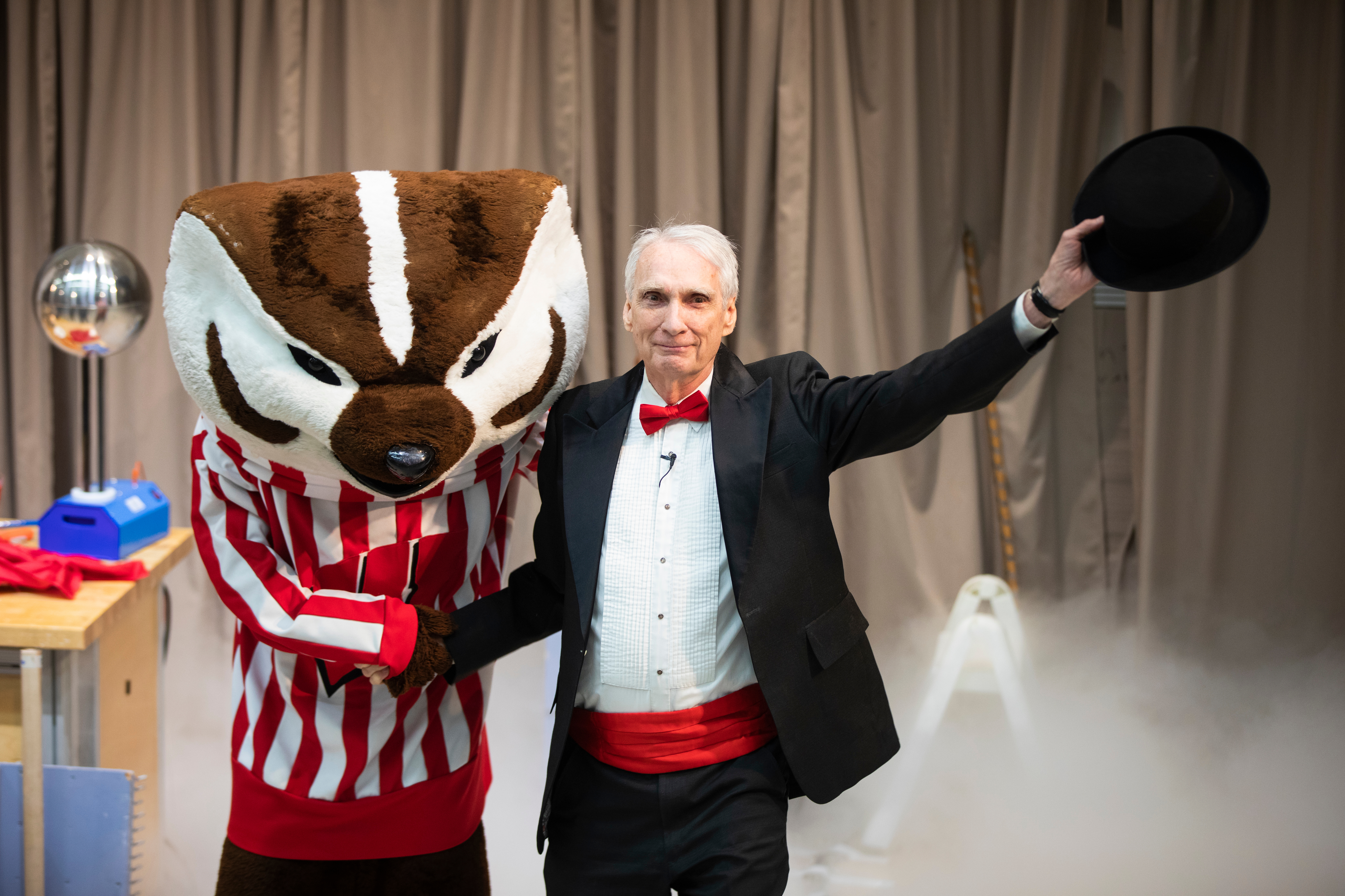 Bucky Badger shakes Clint Sprott's hand as Clint waves to the audience with his hat raised