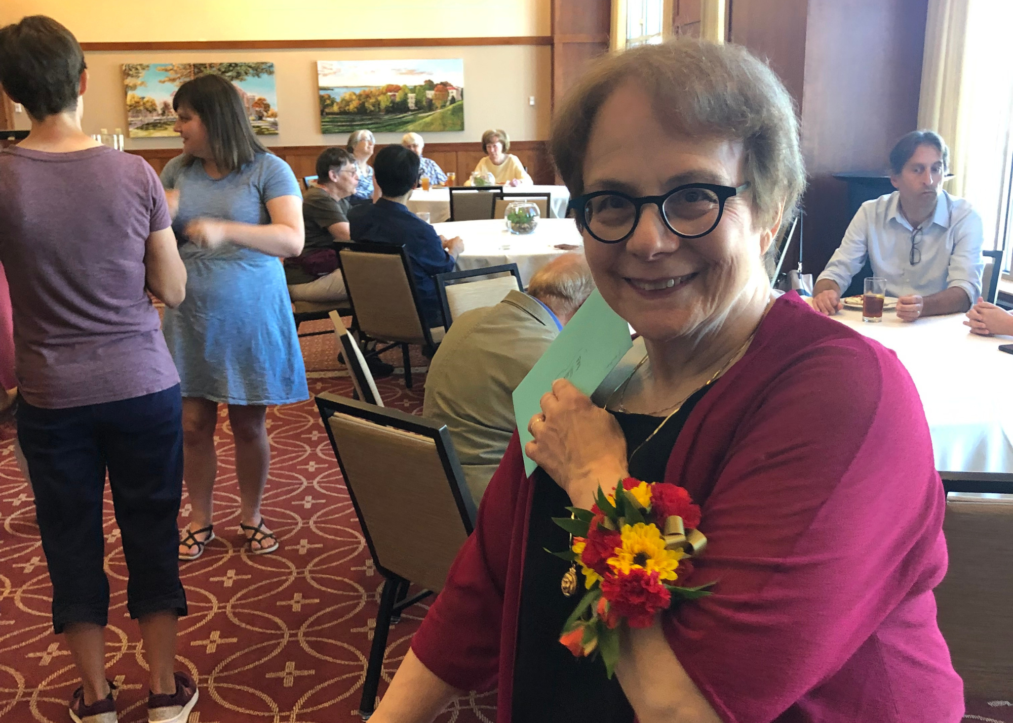 Ellen Jacobson showing off her wrist corsage of red and yellow flowers at her party.