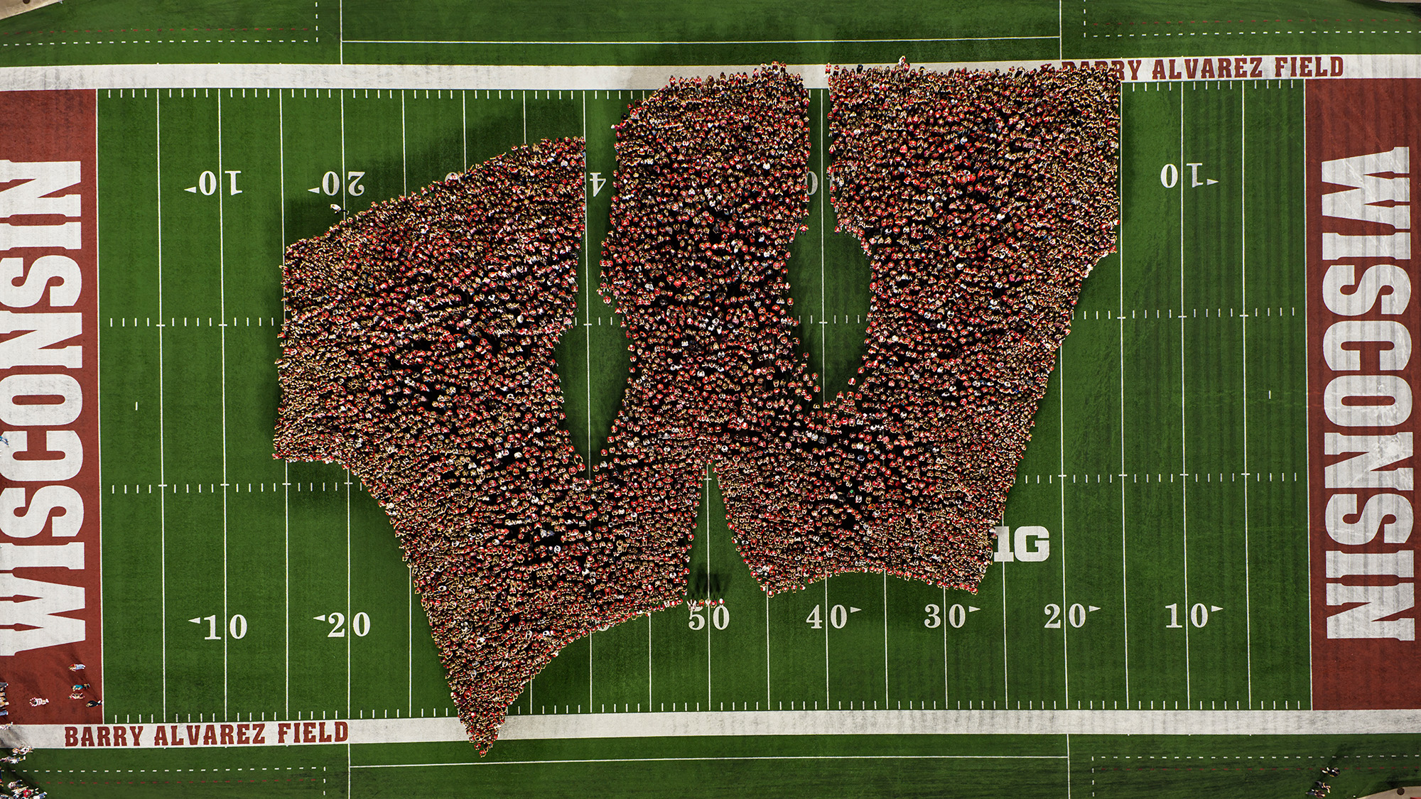 A birds-eye drone photo of students forming a giant "W" on the field at Camp Randall Stadium