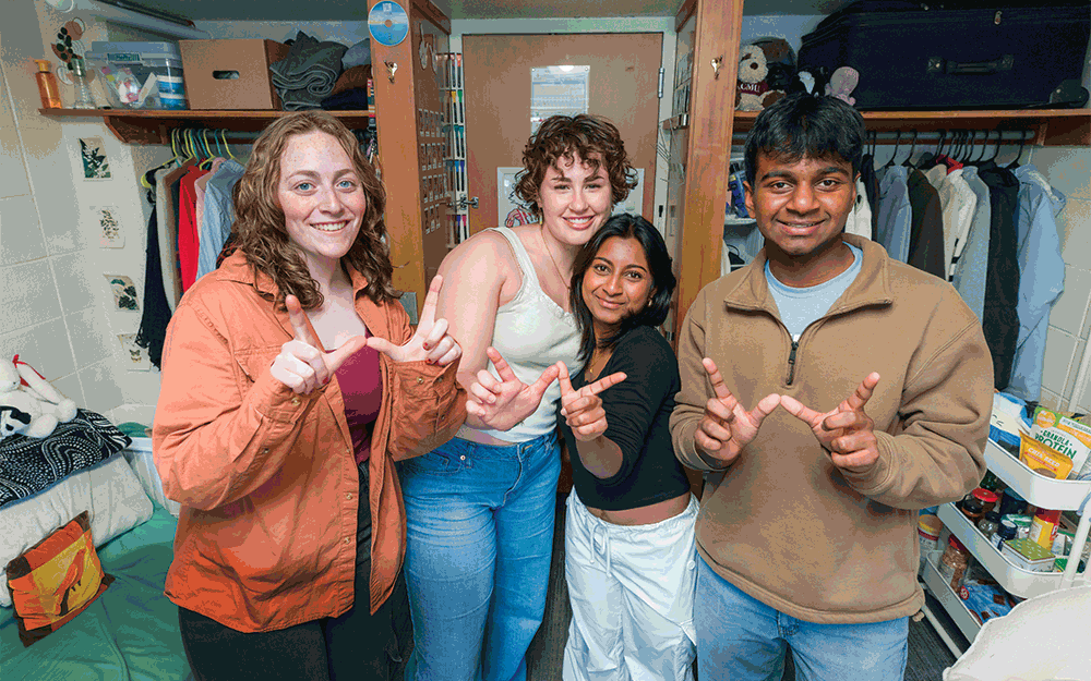 Residents in Cole Residence Hall pose for a picture while making the letter W with their hands with text overlaid reading "Explore the UW–Madison Residence Halls"