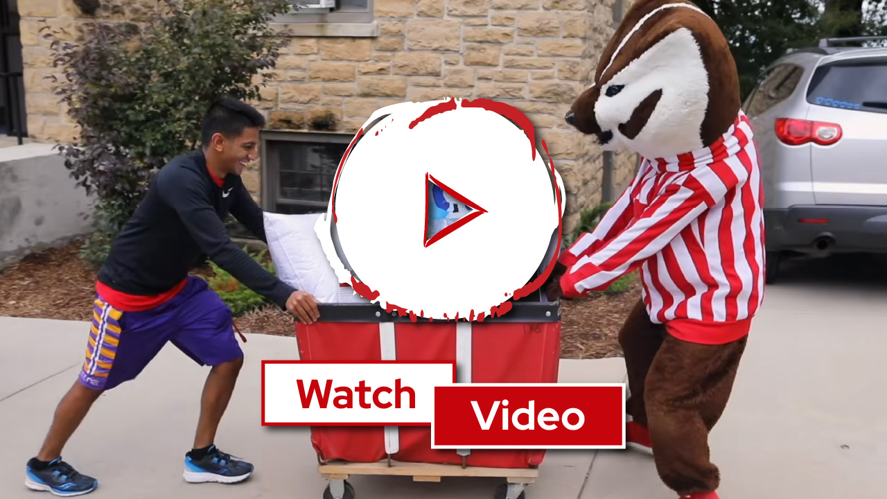 A resident and Bucky moving a cart with a large play button and the words "Watch Video" overlaid